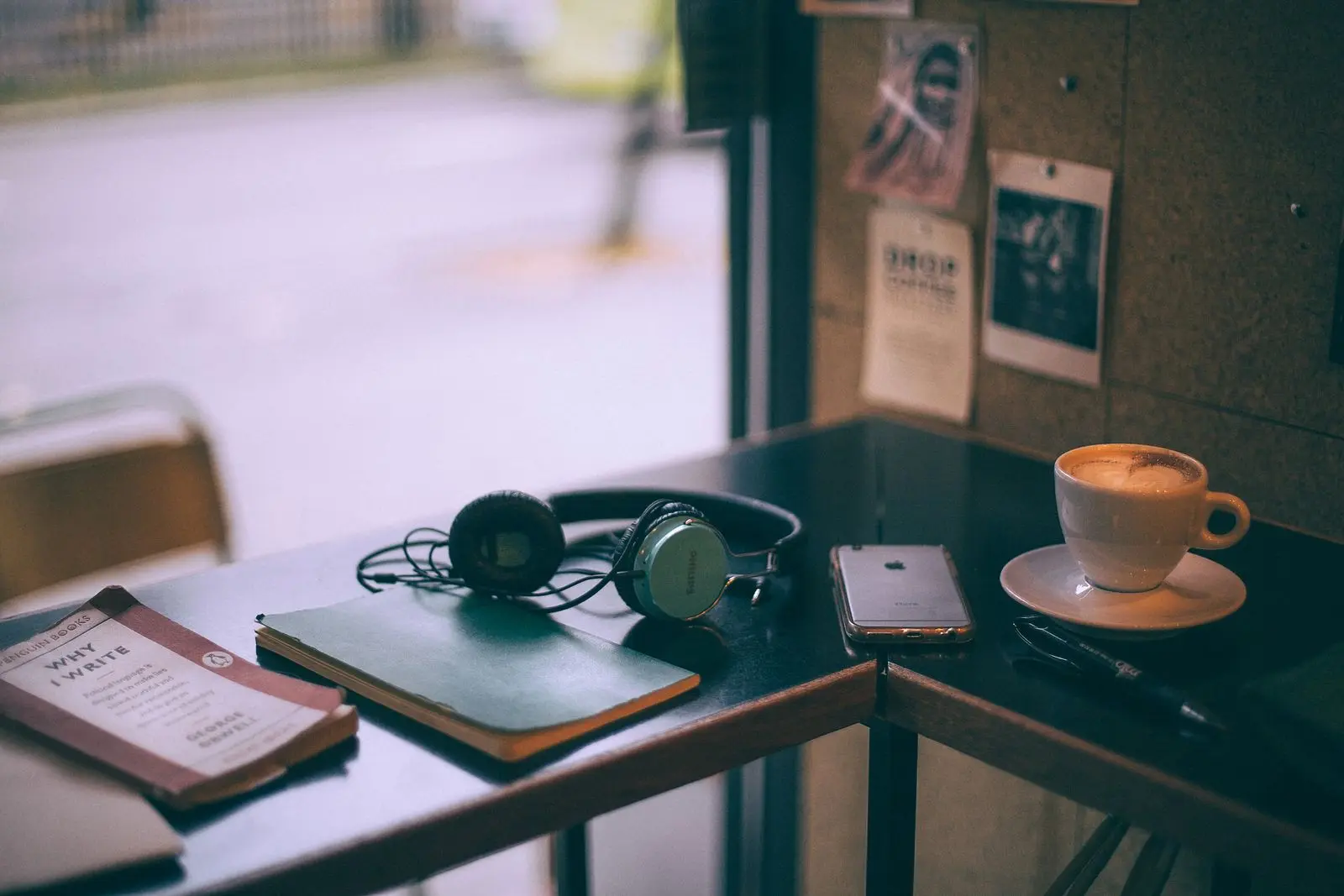 Headphones, notebooks, a phone and a cup of coffee on a café table