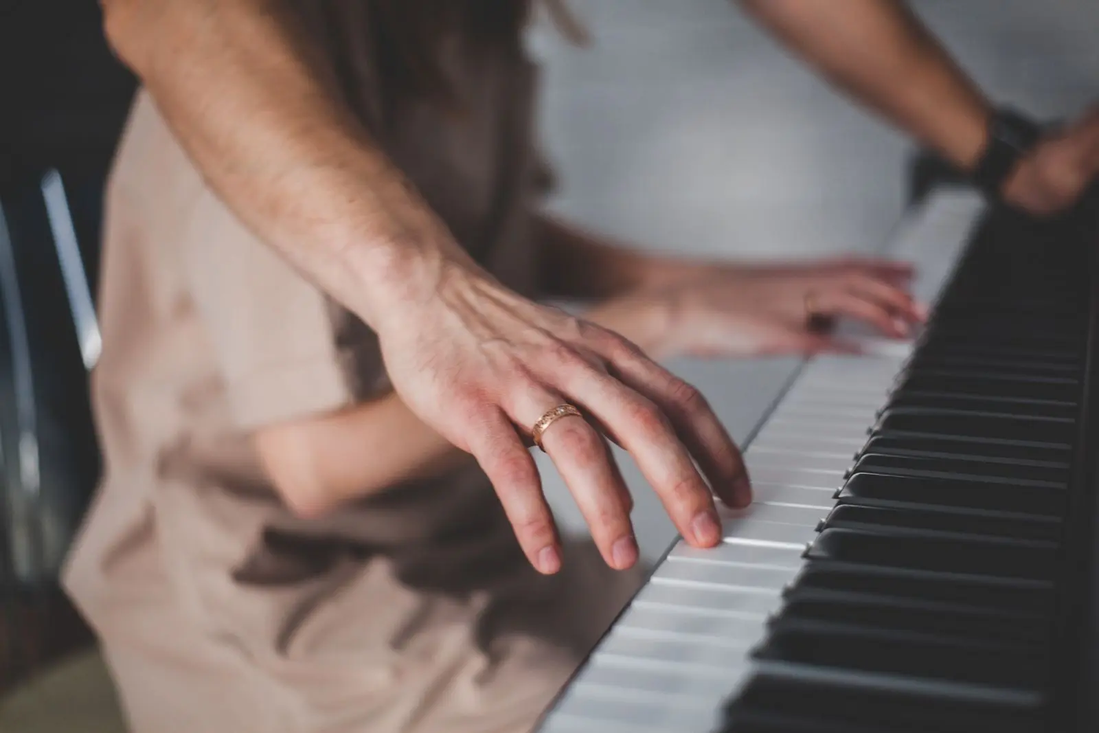 Two people's hands on the keys of the same piano