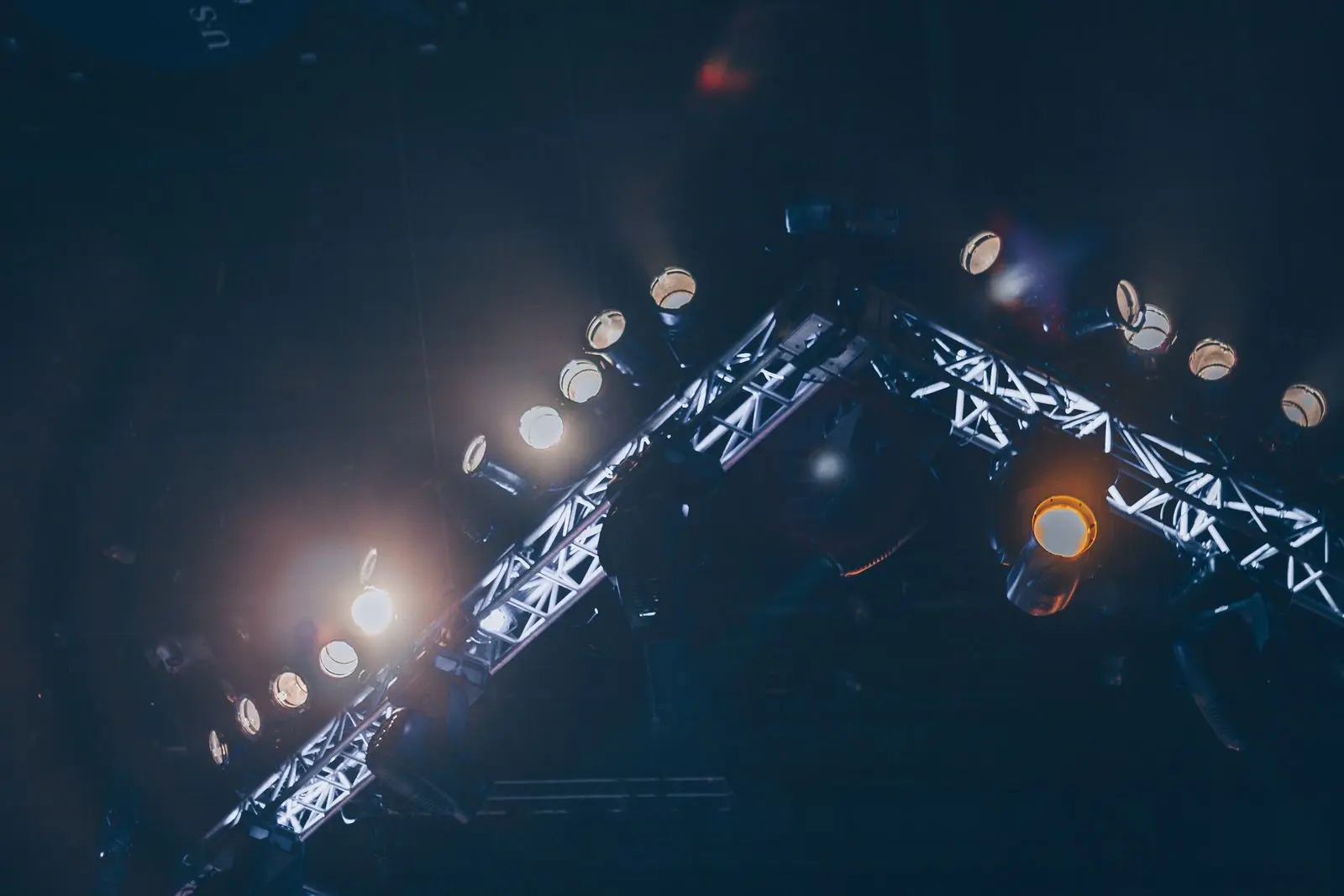 A lighting truss hung with rows of stage lamps, seen from below in the dark