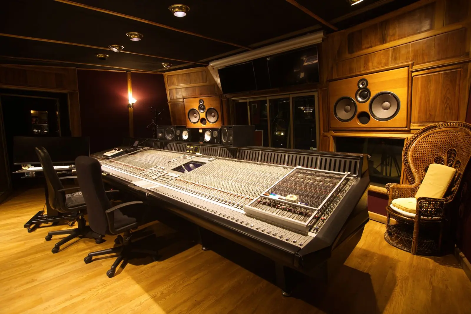 A recording studio control room with a large mixing console