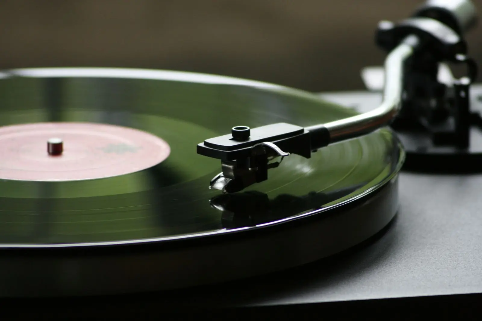 A vinyl record on a turntable with its tonearm beside it
