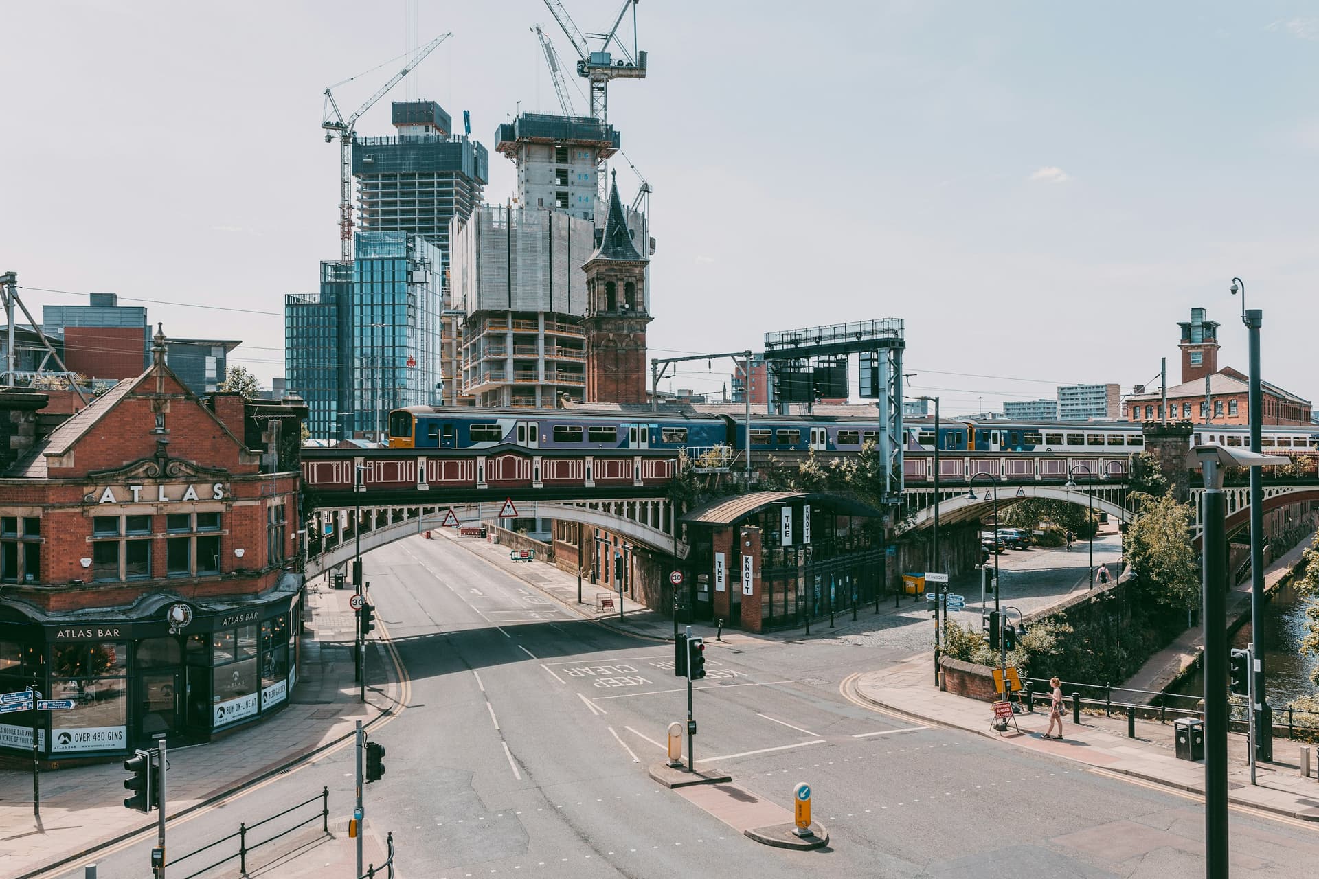 A Manchester street with a railway bridge and rising skyline.