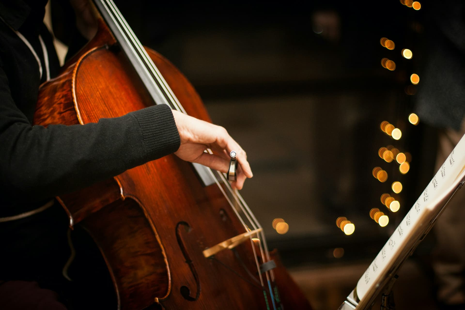 A cellist's hand on the strings in warm light.