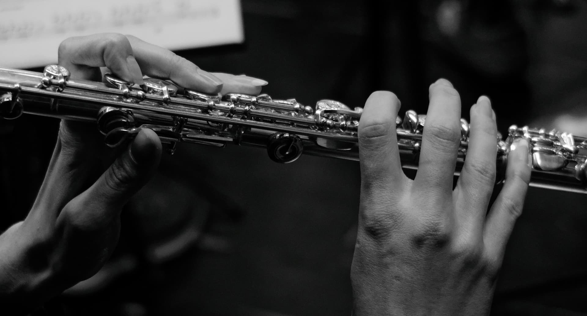 A flautist's hands on the keys of a concert flute.