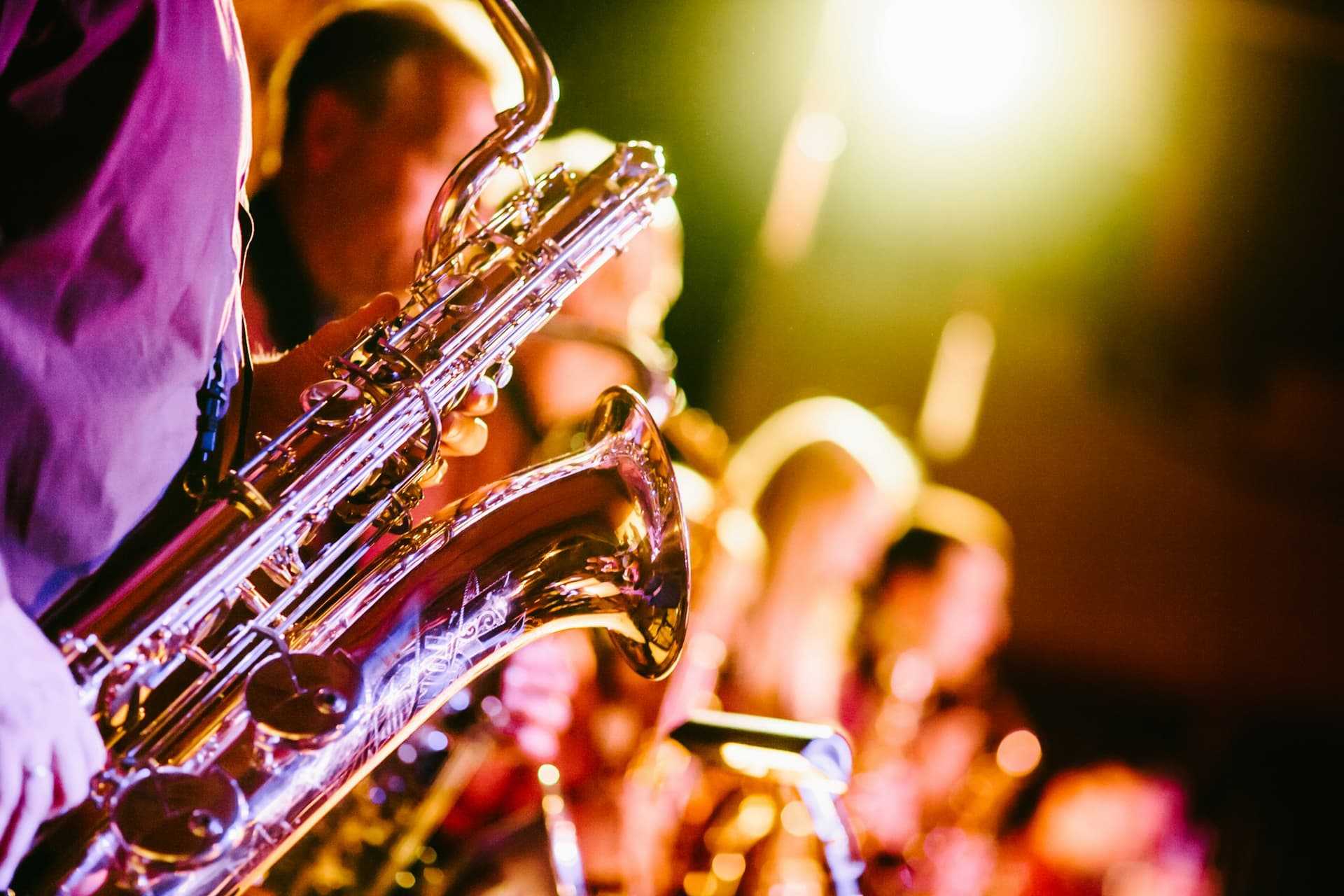 A saxophonist playing live under colourful stage lights.