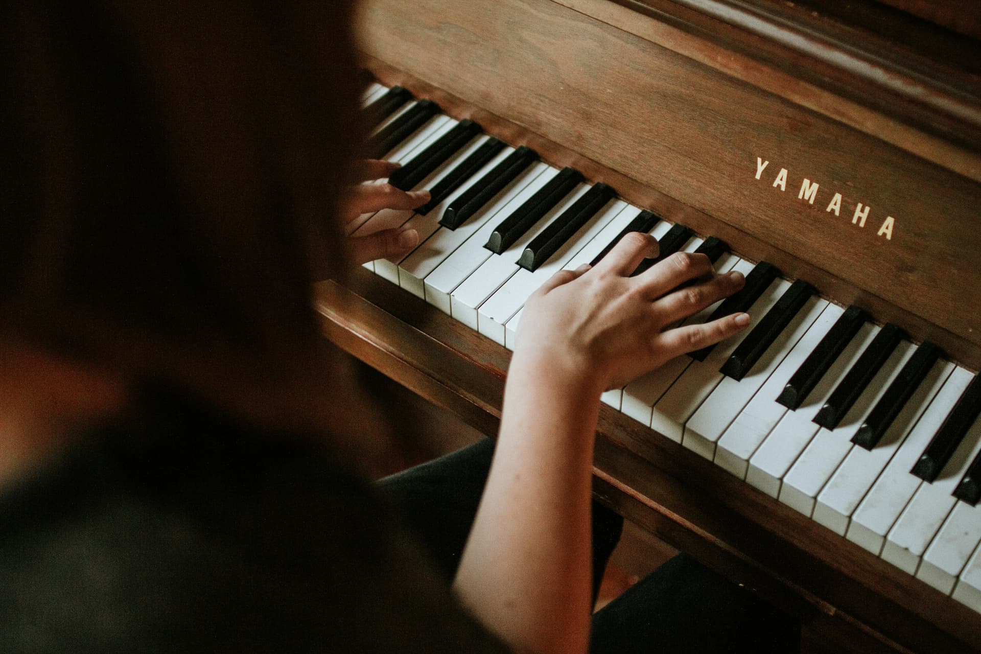 A pianist playing a warm wooden upright piano.