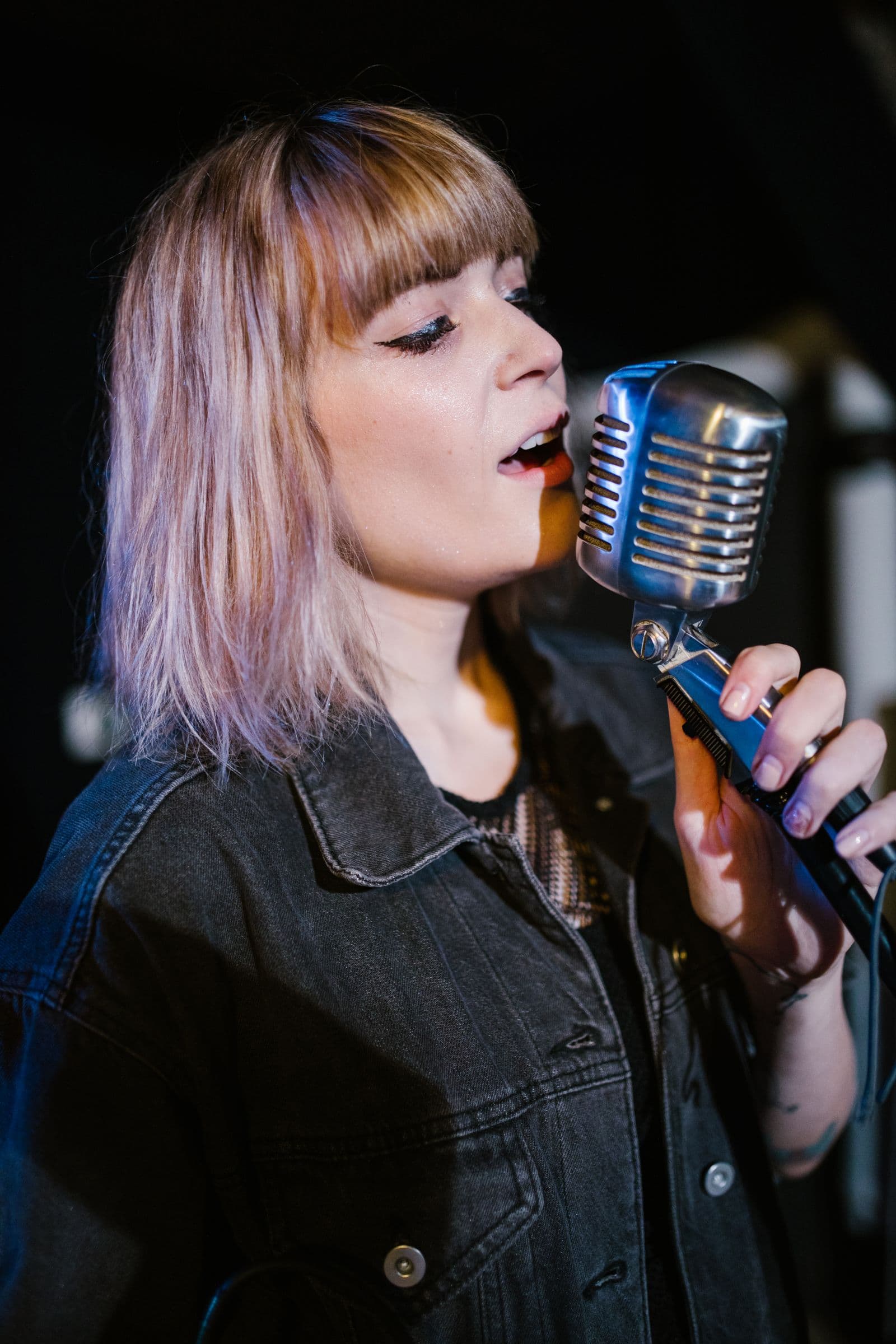 A singer performing at a vintage microphone in warm light.