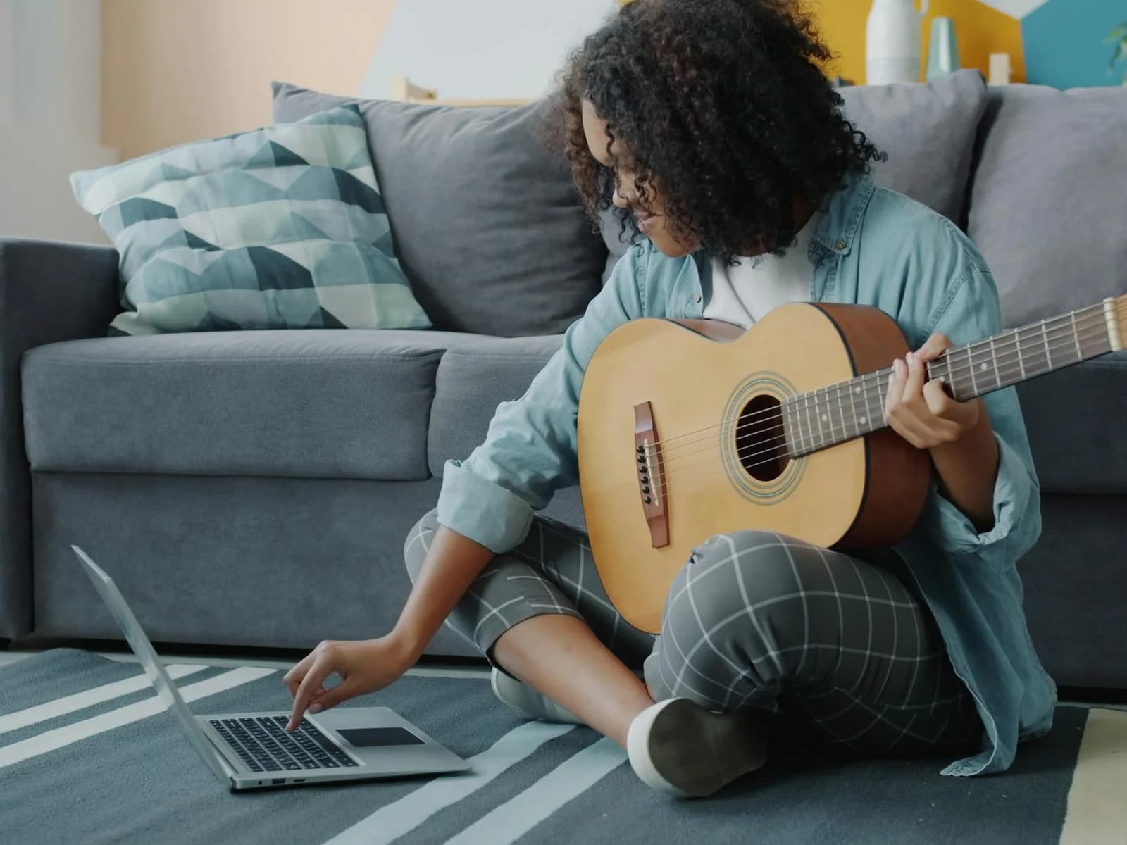 A student comparing music teacher options on a laptop with a guitar nearby.