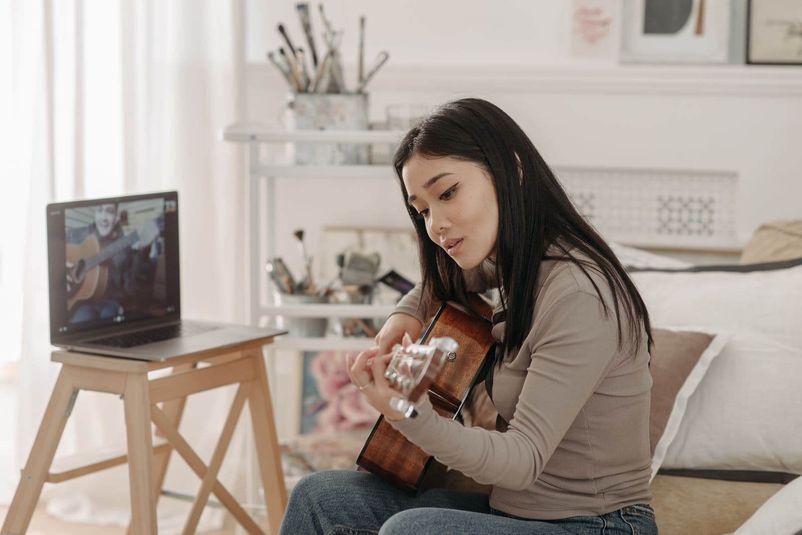 A learner following an online guitar lesson at home.